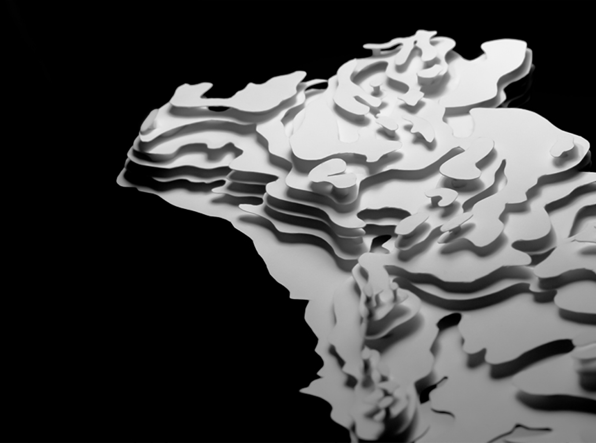 A black and white image showcasing a 3D paper model of Portugal, with a focus on the northen frontiers. The model uses layered paper to represent the varying elevations and contours of the country's landscape.