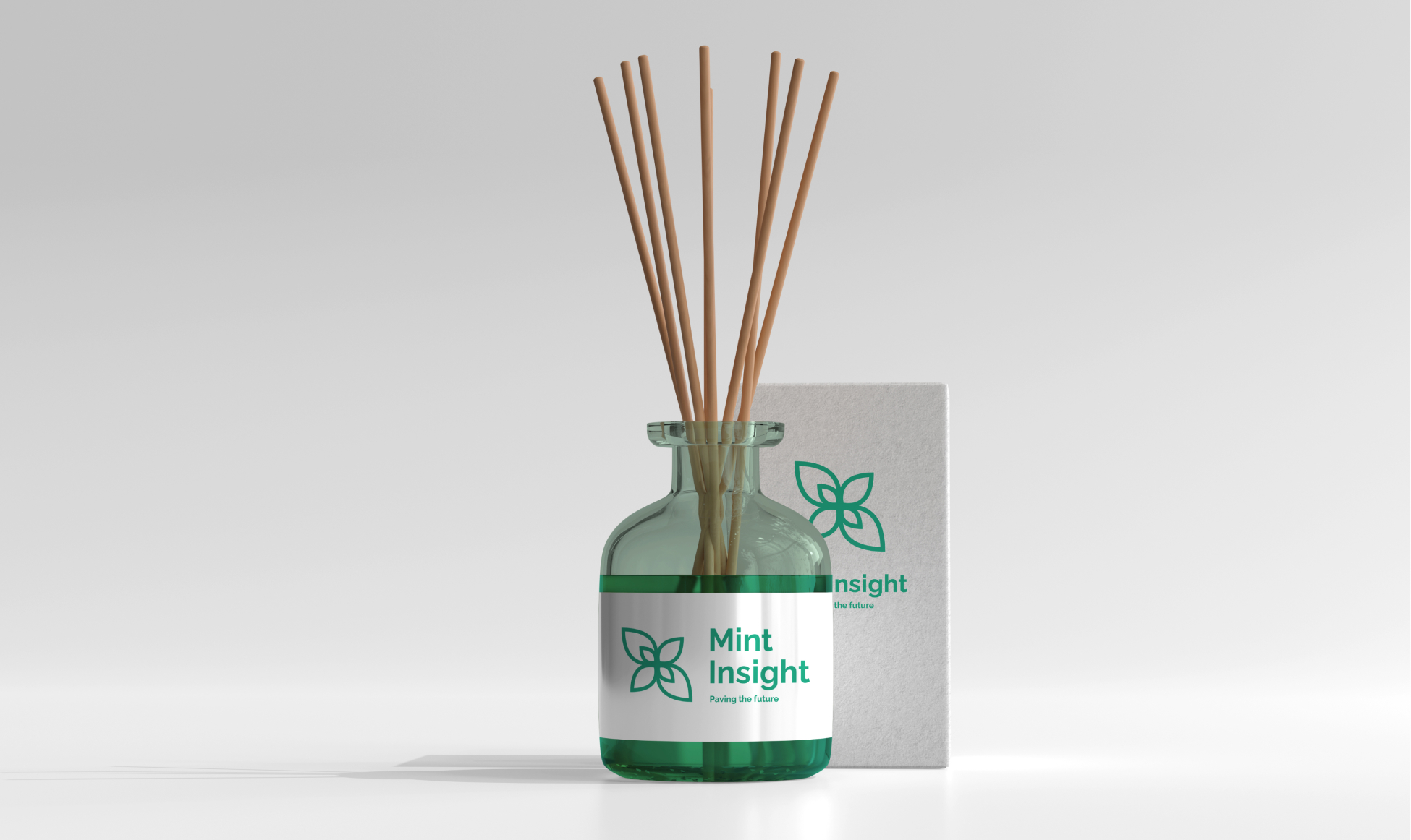 A clear glass diffuser bottle with a green label featuring the Mint Insight logo and the phrase 'Paving the future'. The bottle is filled with reed sticks and is placed next to a white box with the Mint Insight logo