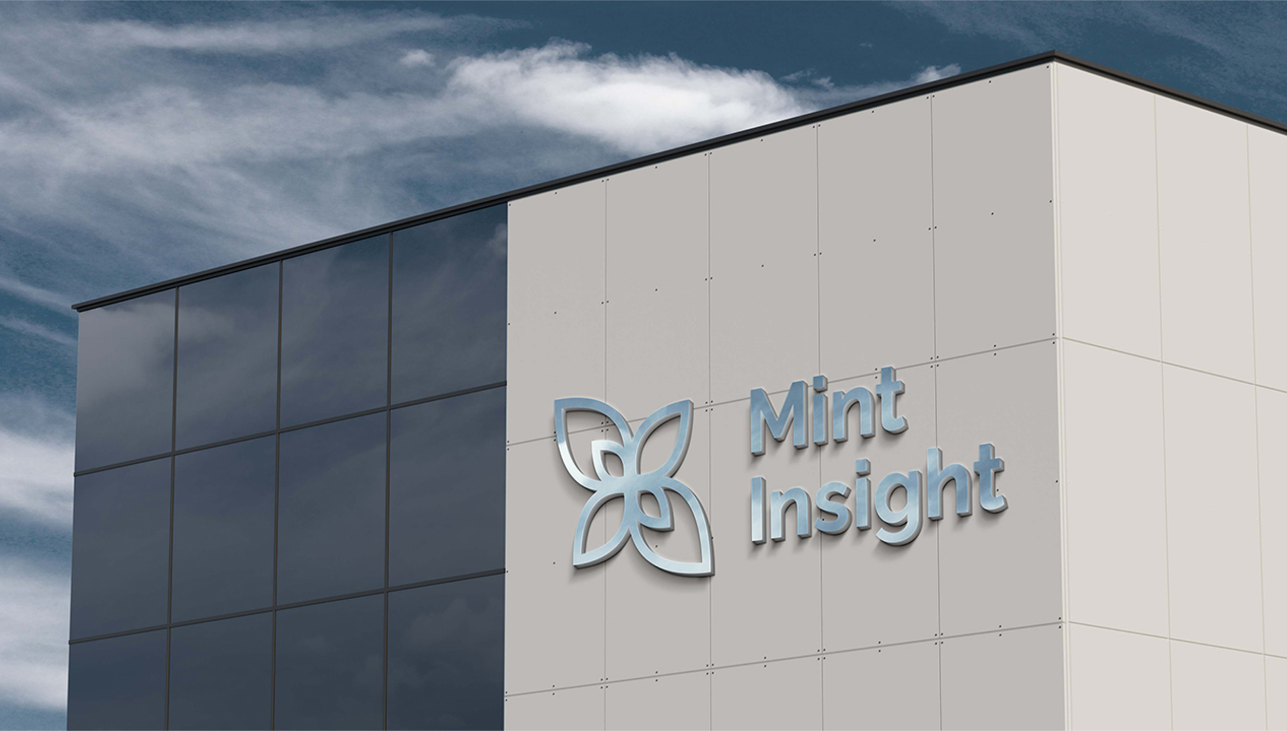 A silver-colored Mint Insight logo mounted on the side of a modern building with a gray facade and a blue sky in the background.