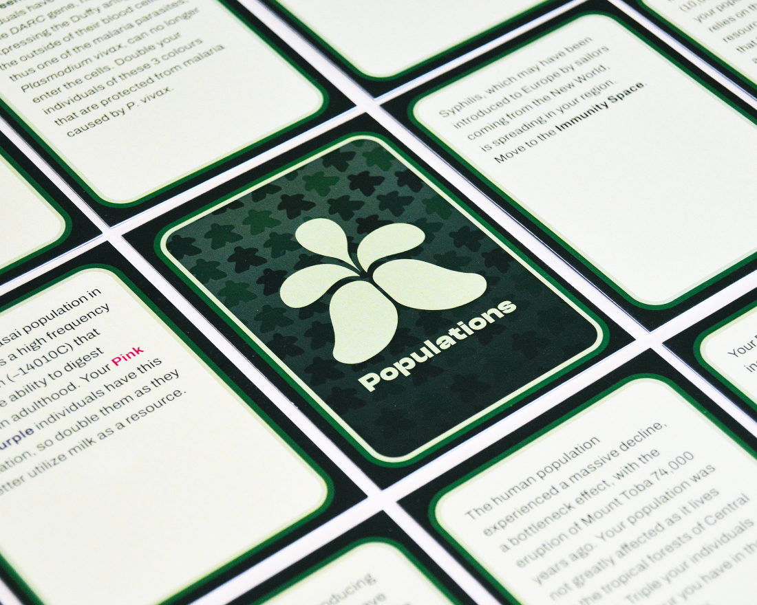 A close-up of cards from the green deck of the Populations board game